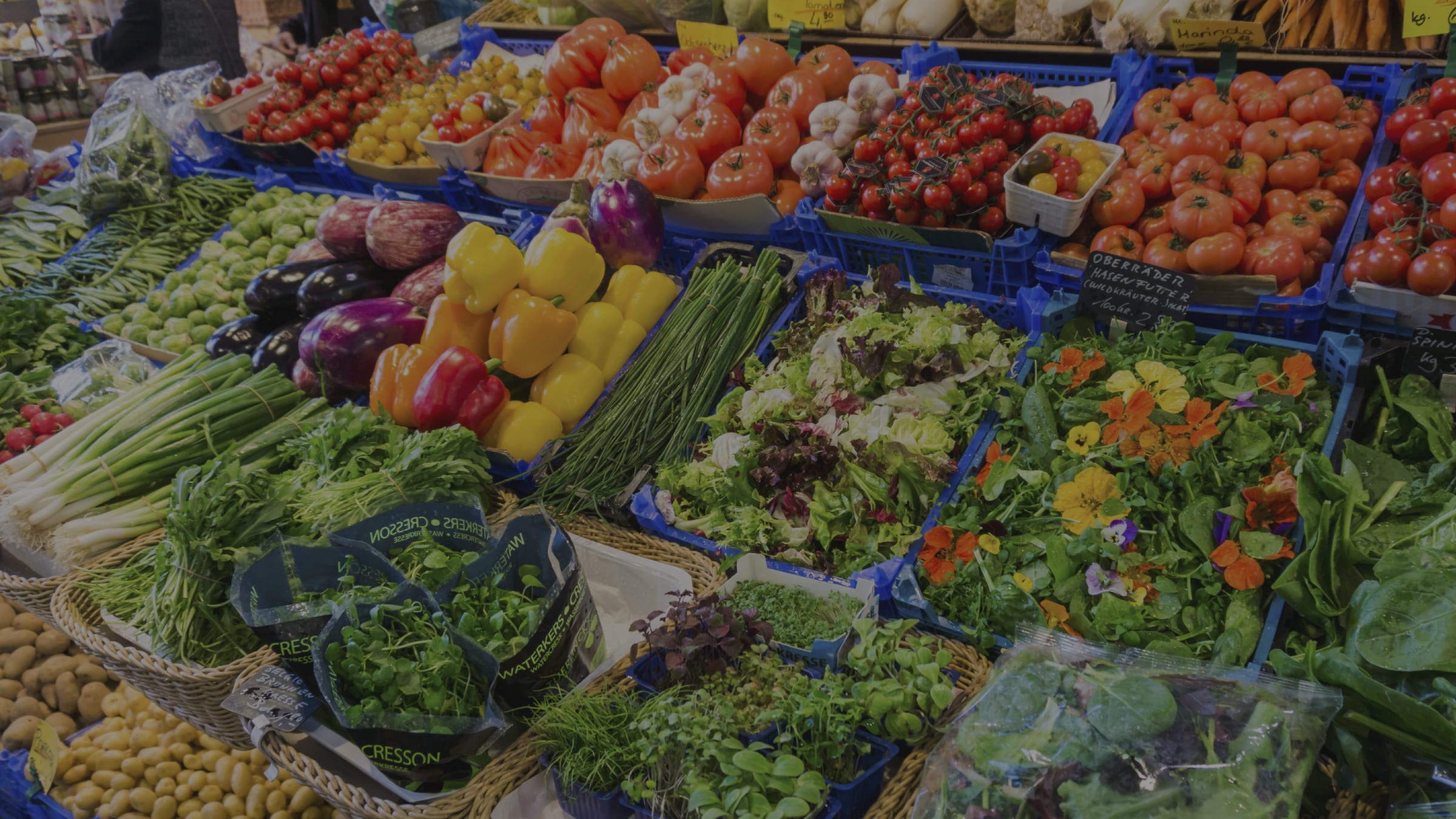 Fresh produce market stall filled with seasonal vegetables, herbs and tomatoes